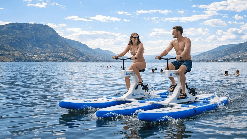 Two people riding water bikes on a lake with mountains in the background. 3