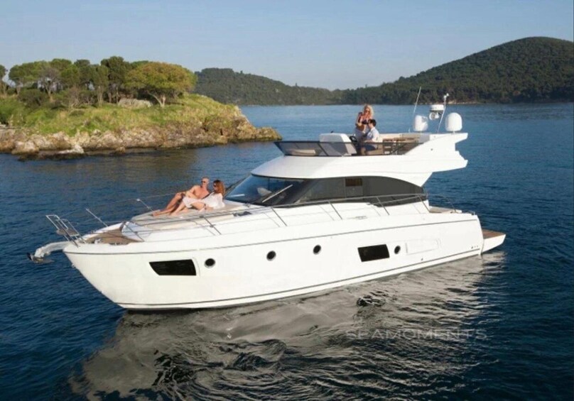A white yacht with a cabin and a deck, floating on calm water with a hilly landscape in the background. 4