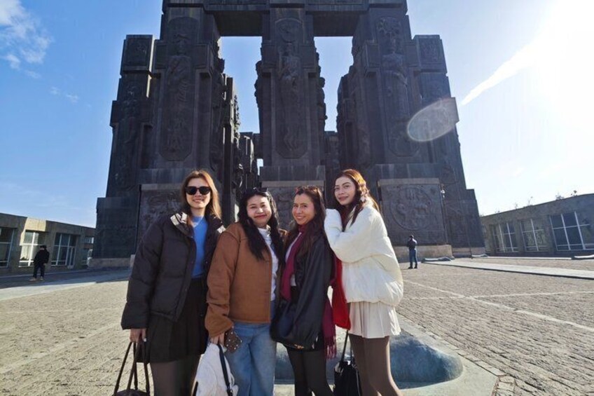 Four people standing in front of a large, historical stone structure. 2