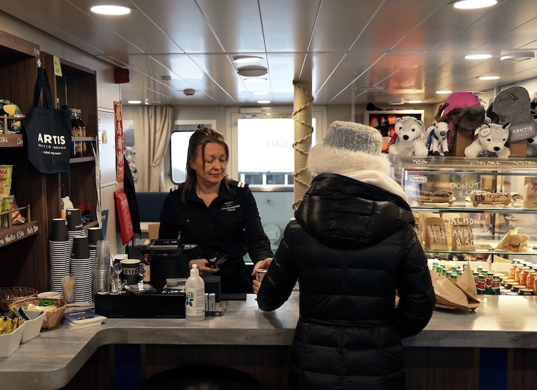 A person in a black jacket interacting with a staff member at a counter in a cafe. 3