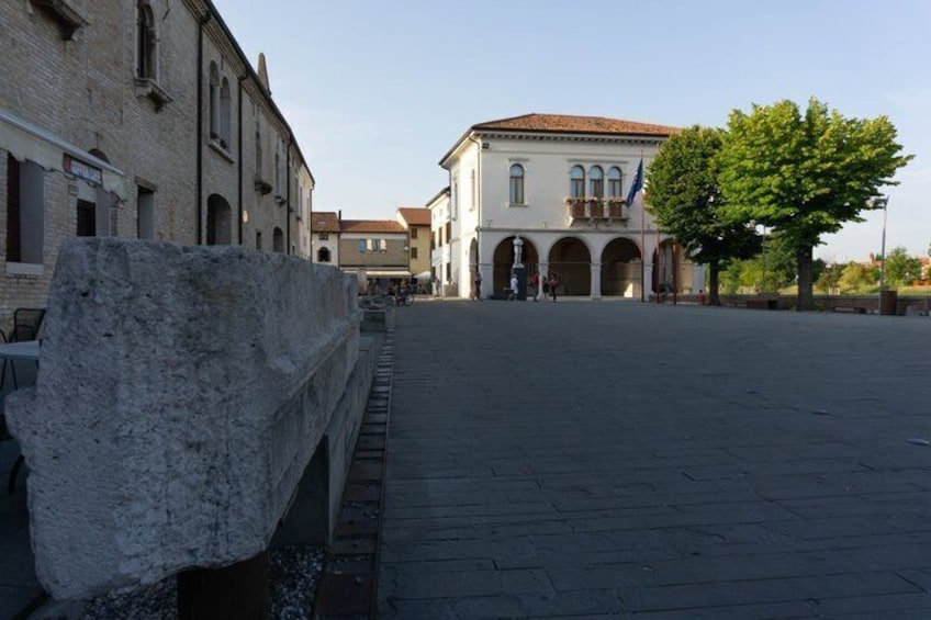 A stone bridge, a plaza with buildings, and a tree. 1