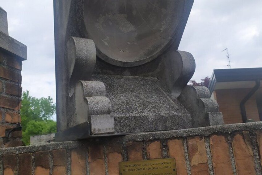 A large concrete structure with a plaque, brick wall, and metal pipes. 2