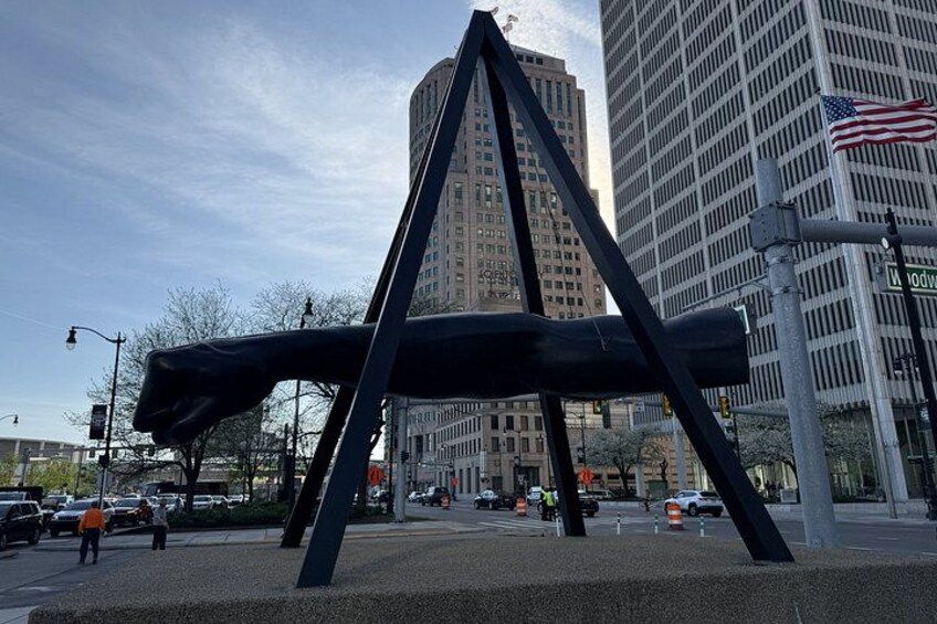 A large metal sculpture in an urban setting with tall buildings and a clear sky. 5