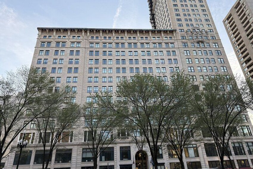 A tall building with many windows, surrounded by trees. 2