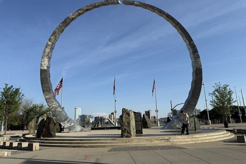 A large circular monument with American flags, surrounded by a plaza with trees and buildings in the background. 2