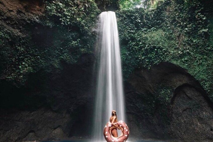 A waterfall with a person sitting on a ring in the foreground. 5