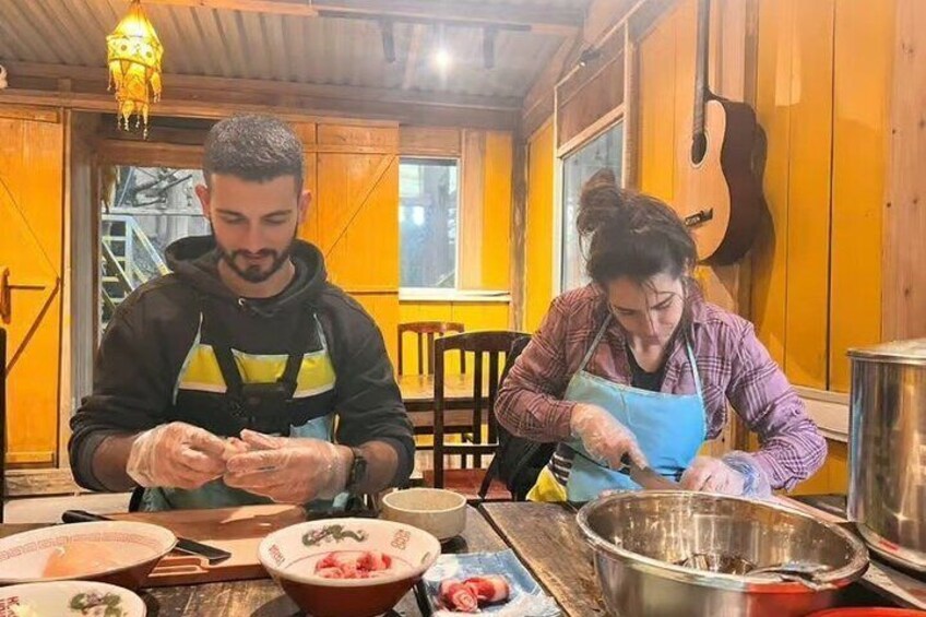 Two people preparing food at a wooden table with bowls and a guitar in the background. 3