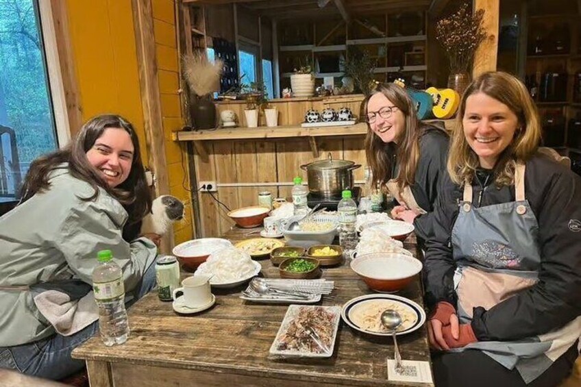 A wooden table with various dishes and drinks, surrounded by people in aprons. 2