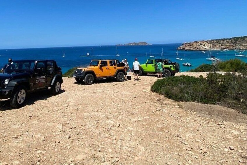 A rocky coastal path with parked vehicles and a clear view of the sea. 4