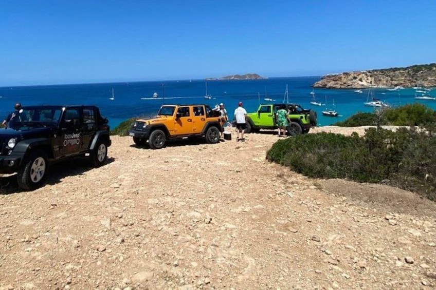 A rocky coastal path with parked vehicles and a clear view of the sea. 3
