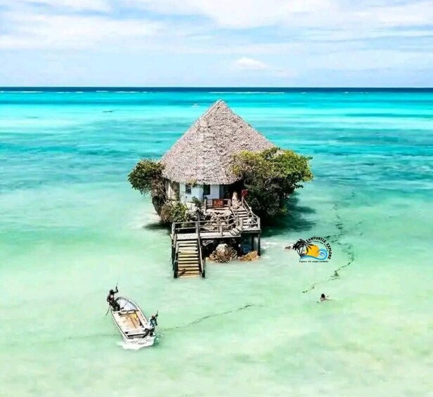 A thatched-roof hut on a small island surrounded by turquoise waters. 1