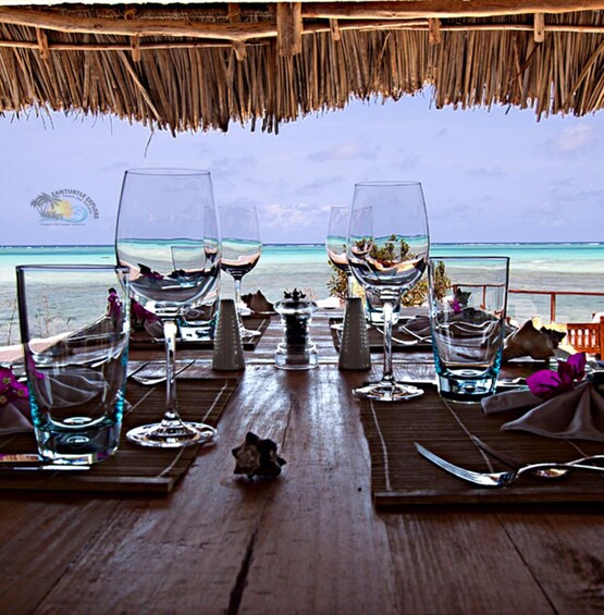 A table set for two with glasses and cutlery, overlooking a beach. 4