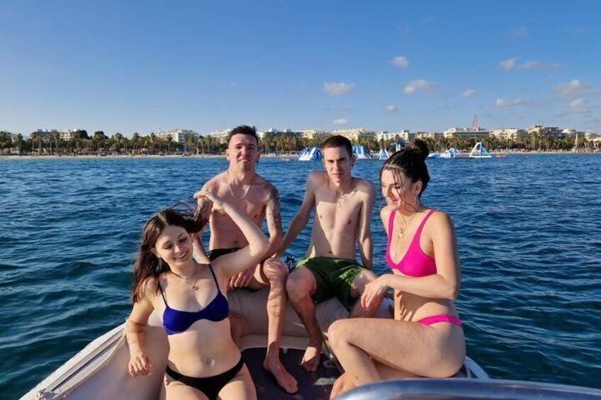 A group of people on a boat in a body of water with a cityscape in the background. 1