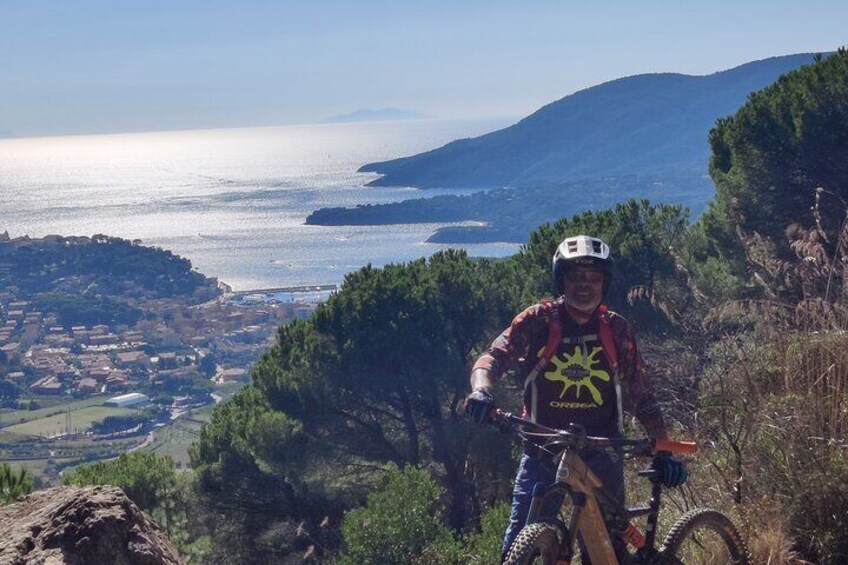 A mountain biker on a trail with a coastal landscape in the background. 5