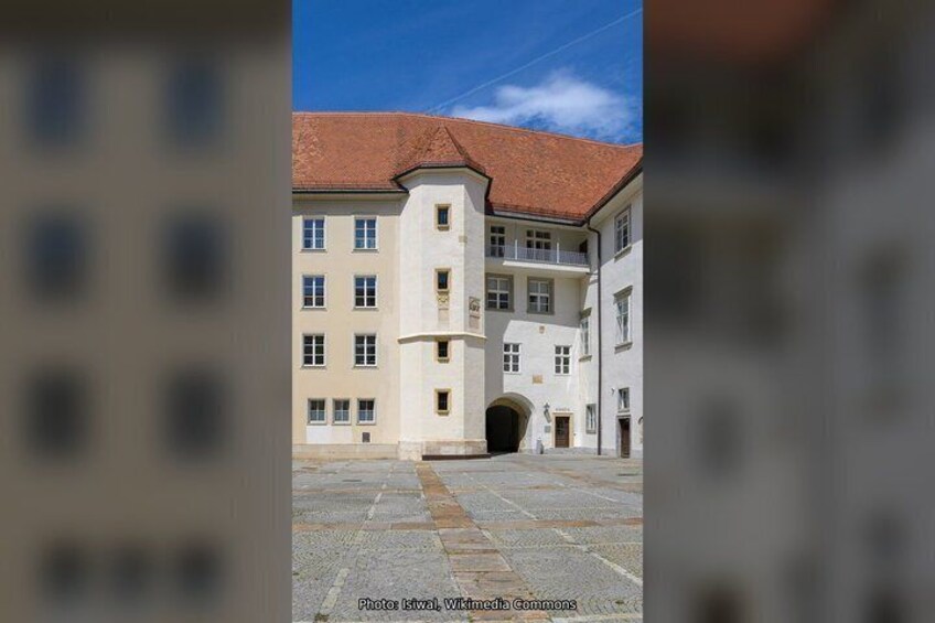 A building with a red-tiled roof and a stone courtyard. 5