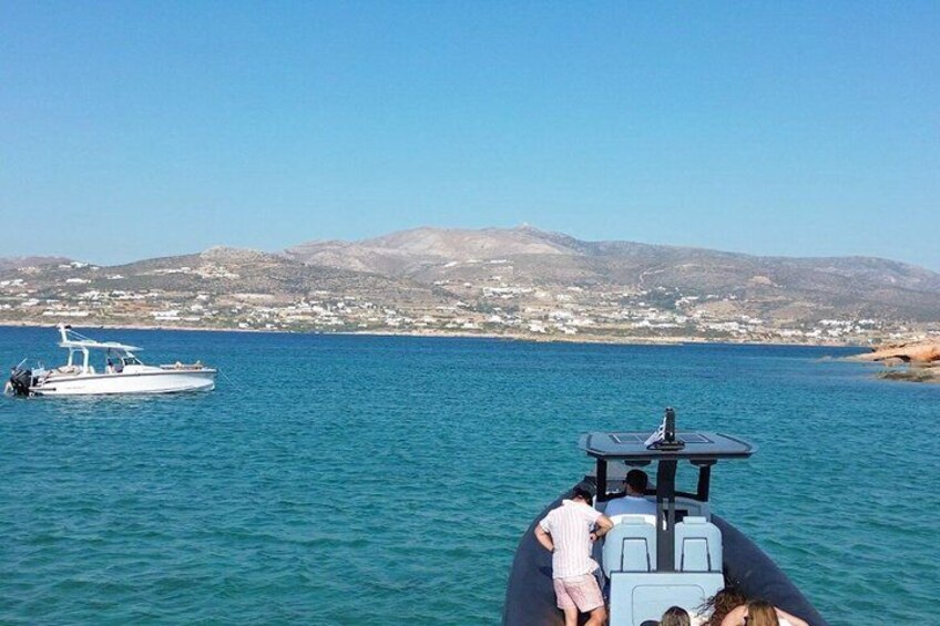 A boat with people on a calm sea, a distant shoreline, and mountains in the background. 3