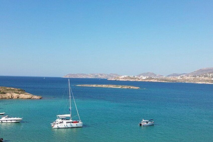 A coastal scene with clear blue waters, a sailboat, and a distant shoreline with buildings. 4