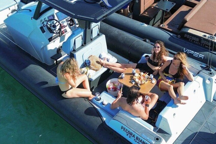 A group of people on a boat with a table, some drinks, and a steering wheel. 1