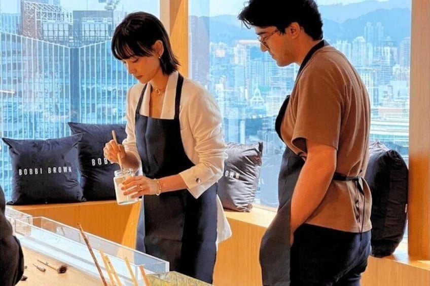 A person preparing a drink with a shaker and a spoon, another person standing beside them, and a cityscape view through large windows. 2