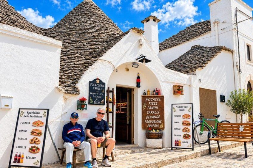 Un edificio italiano tradicional con tejado de piedra, un letrero de panadería y una bicicleta estacionada afuera. 2