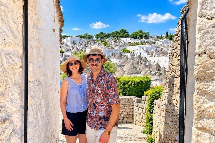 Una pareja parada en un umbral, con vistas a un pueblo blanco y colinas verdes al fondo. 4