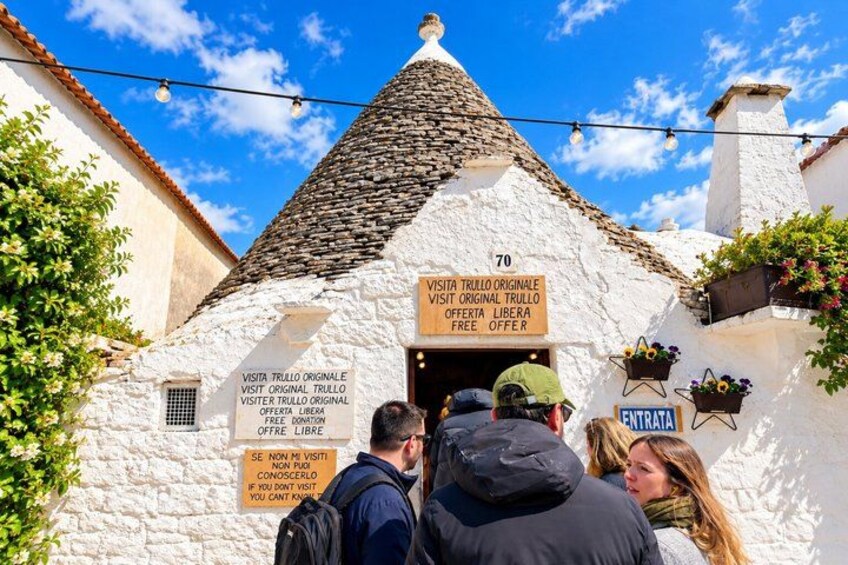 Un edificio de piedra blanca con techo cónico, carteles que indican visita gratuita y un letrero para la entrada. 5