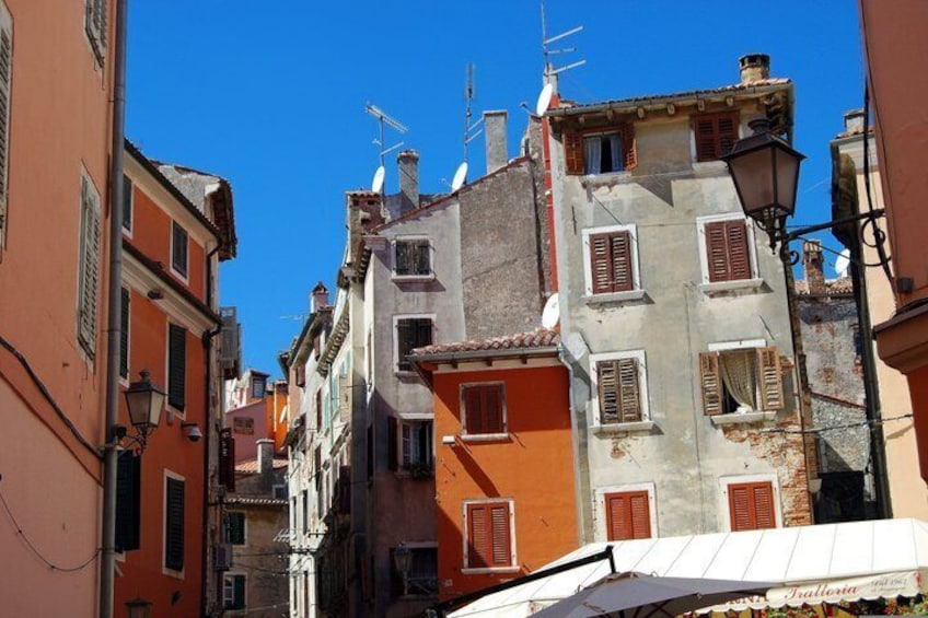 A narrow street with colorful buildings, a clear blue sky, and a street lamp. 2