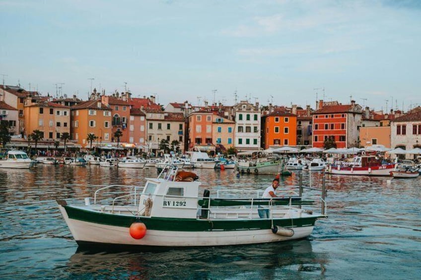 A boat with the registration number RV 1292 docked in a marina with colorful buildings in the background. 5