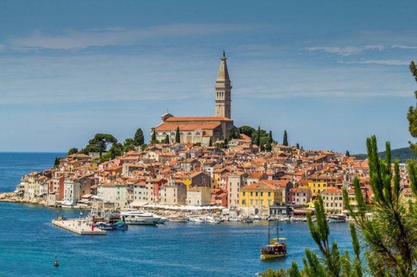A coastal town with a prominent tower, colorful buildings, and boats in the harbor. 1