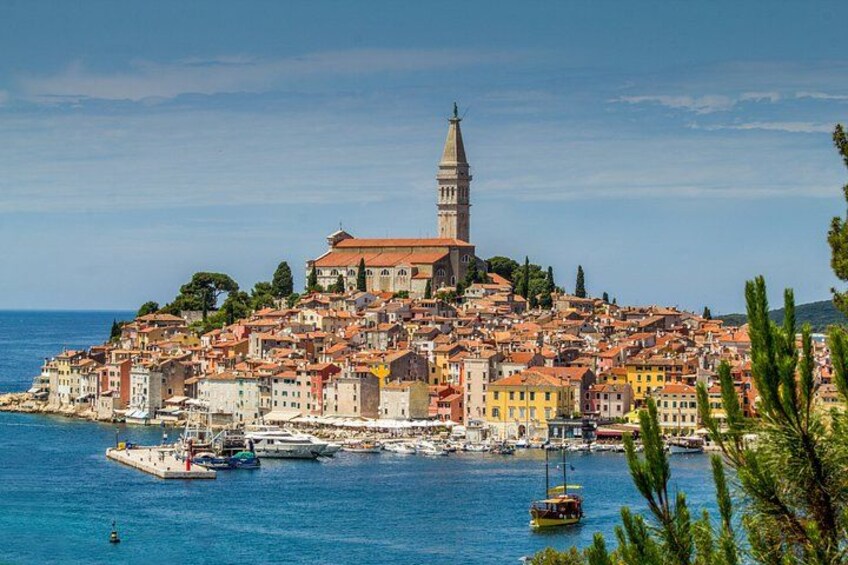 A coastal town with a prominent church tower, colorful buildings, and boats in the harbor. 1