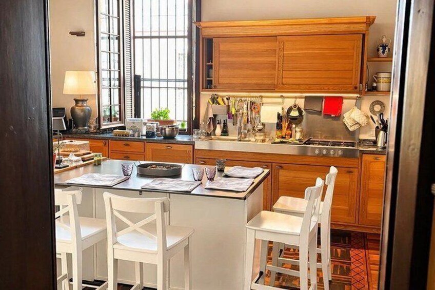 A kitchen with wooden cabinets, a stove, and a dining area with chairs. 4