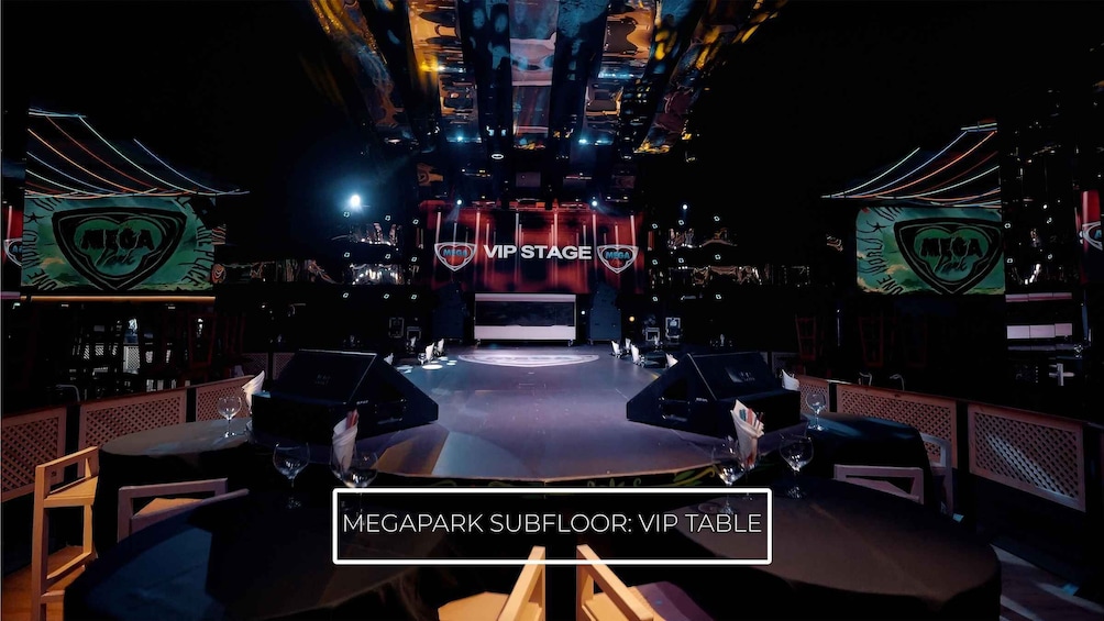 A VIP stage area with a dark, atmospheric setting, including a VIP table and branded signage. 2