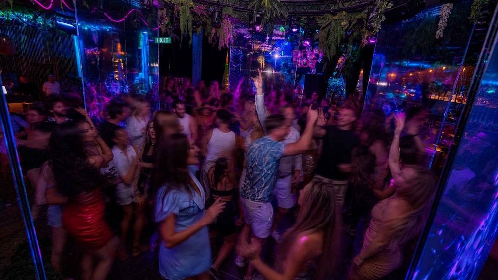 A crowded indoor party with neon lights and a jungle theme. 5