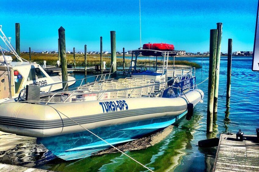 A boat docked at a pier with a clear blue sky and calm water. 3