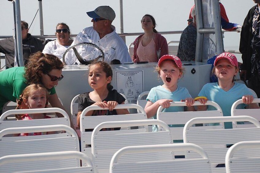 A boat with people on board, some wearing hats, and metal railings in the foreground. 2