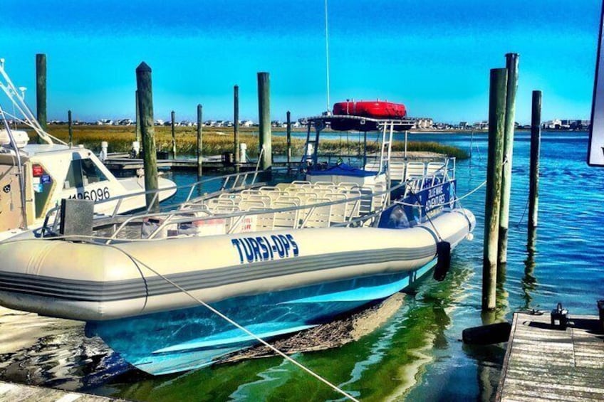 A boat docked at a pier with a clear blue sky and calm water. 5