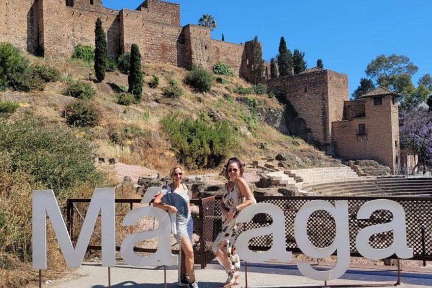 A historical site with ancient ruins and a large sign reading 'Málaga.' 5