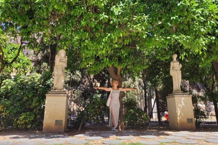 A person standing between two statues under a tree. 4
