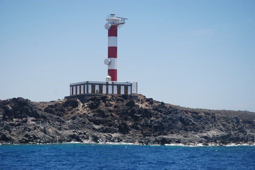 A lighthouse on a rocky outcrop with the ocean in the foreground. 3