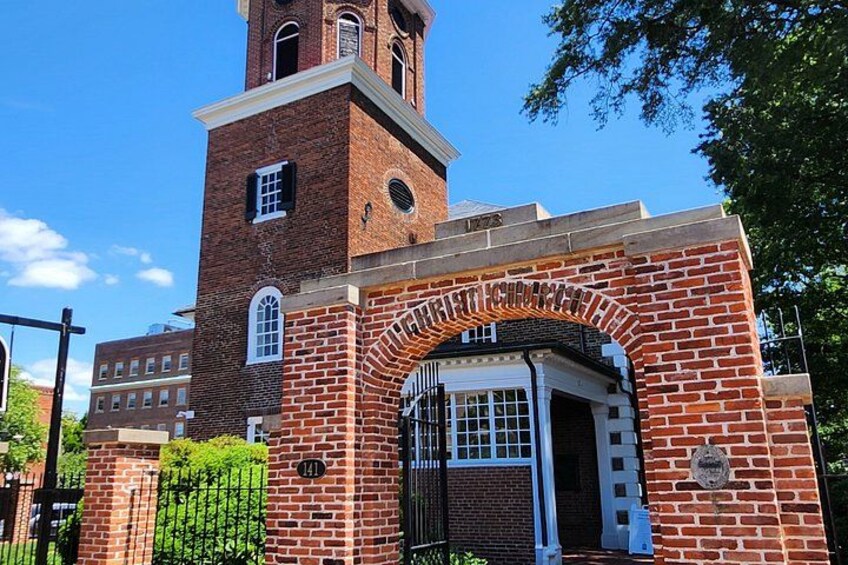 A brick building with a tower, an arched entrance, and a plaque. 3