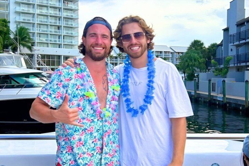 Two people standing by a boat with a marina and buildings in the background. 2