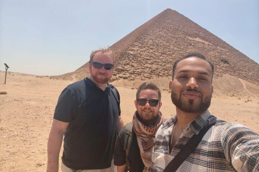 Three people standing in front of a pyramid. 4