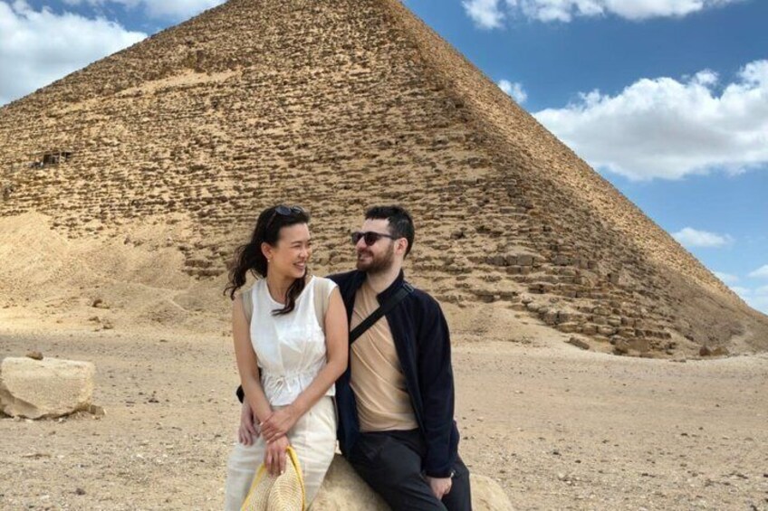 A couple sitting in front of a large pyramid. 3