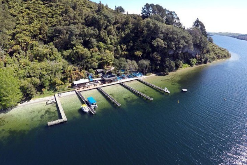 An aerial view of a lake with a dock, boats, and a forested island. 4