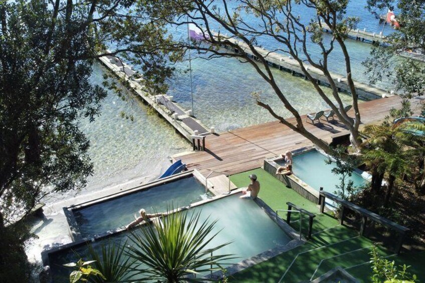 A pool area with clear water, wooden decks, and lounge chairs. 1