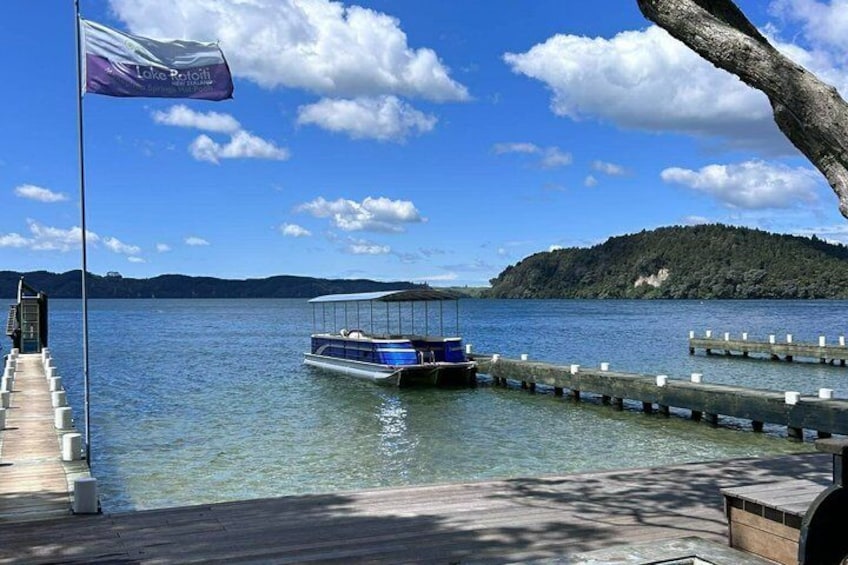A boat docked at a pier with a flag, a clear sky, and a forested island in the background. 5