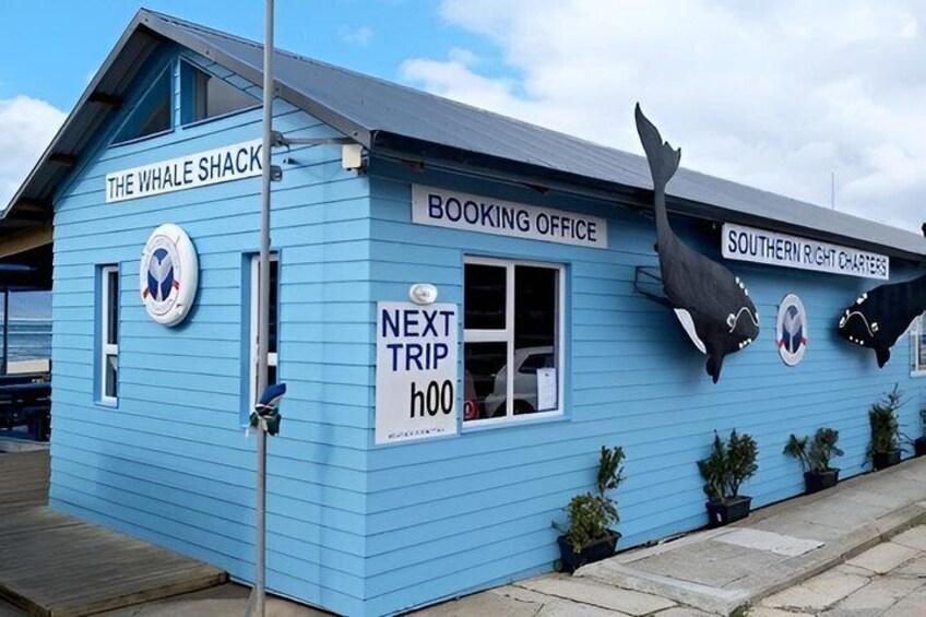 A blue building labeled 'The Whale Shack' with a 'Booking Office' and 'Southern Right Charters' signs, and a whale decoration on the side. 2