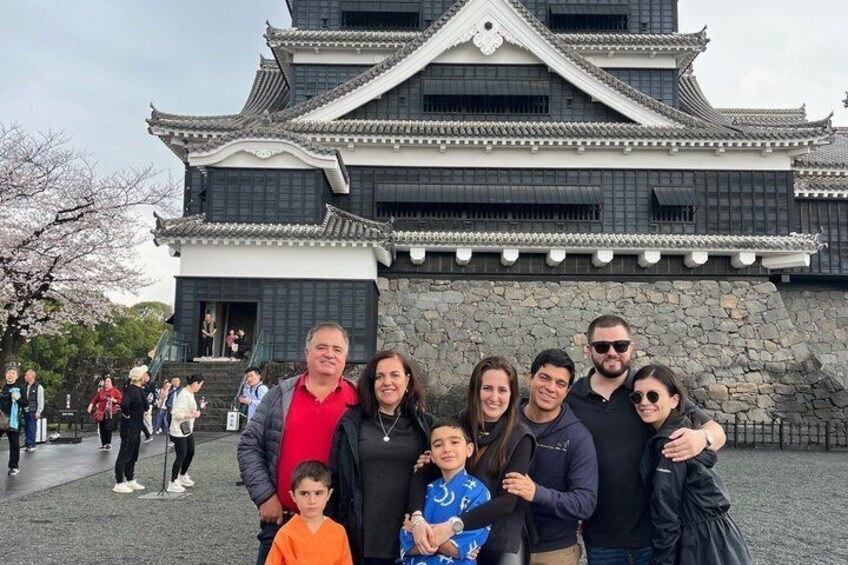 A family in front of a traditional Japanese building with a stone base and tiled roof. 5