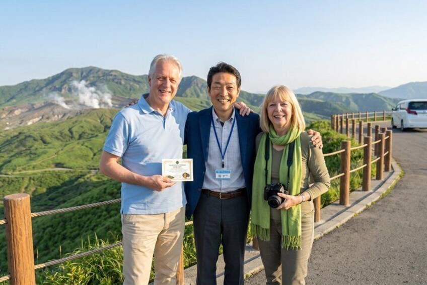Three people standing on a roadside with a mountainous landscape in the background. 1