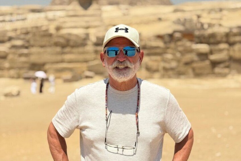 A man standing in a desert with ancient rock formations in the background. 5